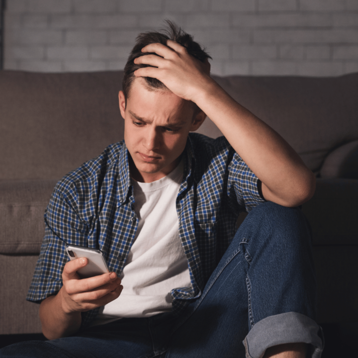 Frustrerad man som tittar på mobilen